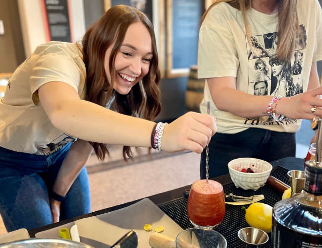 Female mixing cocktail that she created herself during Cocktail Class