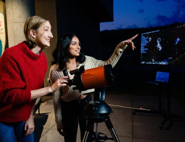 Two women looking through a telescope 