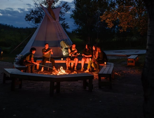 A teepee with a fire burning outside at nighttime