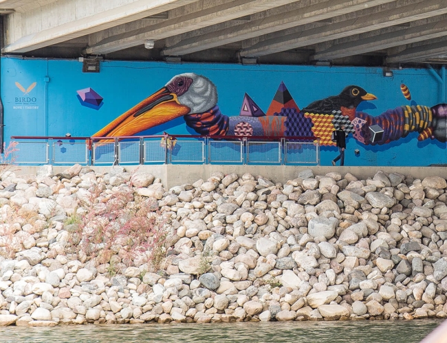 The underside of a bridge painted with a colourful mural.