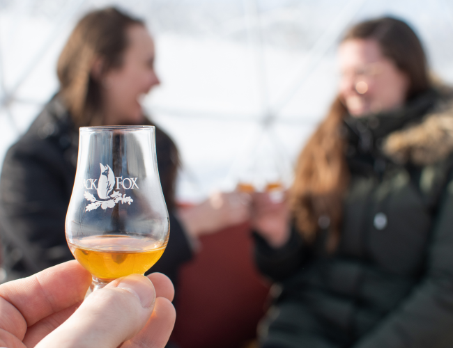 Whisky Glencairn glass filled with whisky with two smiling females celebrating event.